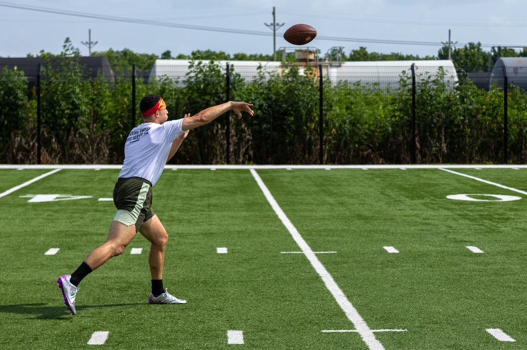 U.S. Marine Corps Capt. Kenneth Belmont, assistant supply officer with Force Headquarters Group, Marine Forces Reserve, passes the football to his teammates during the Battle of The Branches at the New Orleans Saints Practice Facility, Metairie, Louisiana, July 1, 2025. Battle of The Branches consisted of multiple events, the event included flag football, tug-of-war, 40-yard dash, sprint relay, distance throwing and a push up competition. (U.S. Marine Corps photo by Cpl. Aaron TorresLemus)