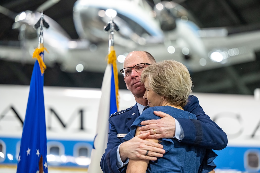 Gen. Richardson in service dress uniform hugs his wife Dede in a blue dress