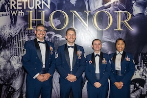 Four Air Force members pose for a group photo in service dress uniforms