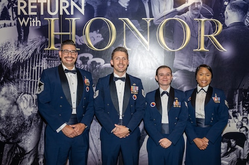 Four Air Force members pose for a group photo in service dress uniforms