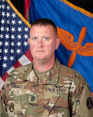 Army command sergeant major posing for official portrait photo in combat uniform with the US flag and Army Aviation flag in the background.