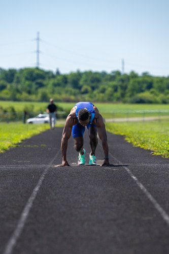 Capt. Banks crouches before sprinting towards the viewer wearing a blue track outfit with USA on the chest