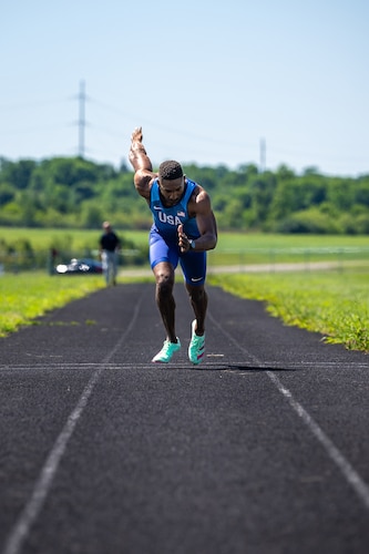 Capt. Banks sprints towards the viewer wearing a blue track outfit with USA on the chest