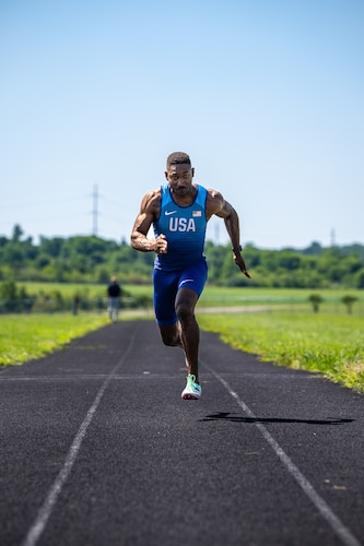 Capt. Banks sprints towards the viewer wearing a blue track outfit with USA on the chest