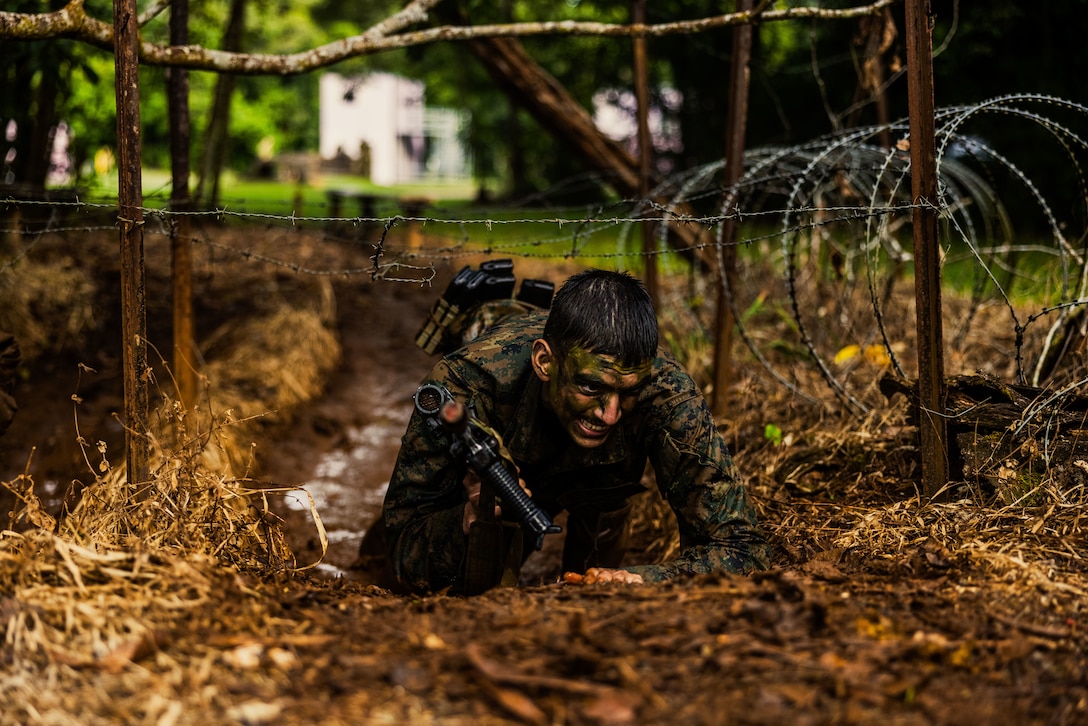 U.S. Marine Corps Lance Cpl. Damian Andrade, a motor vehicle operator with Kilo Battery, 3rd Battalion, 11th Marine Regiment, Marine Rotational Force – Darwin 25.3, crawls under barbed wire as part of True Grit during jungle warfare training at the Combat Training Centre in Tully, Australia, June 26, 2025.
