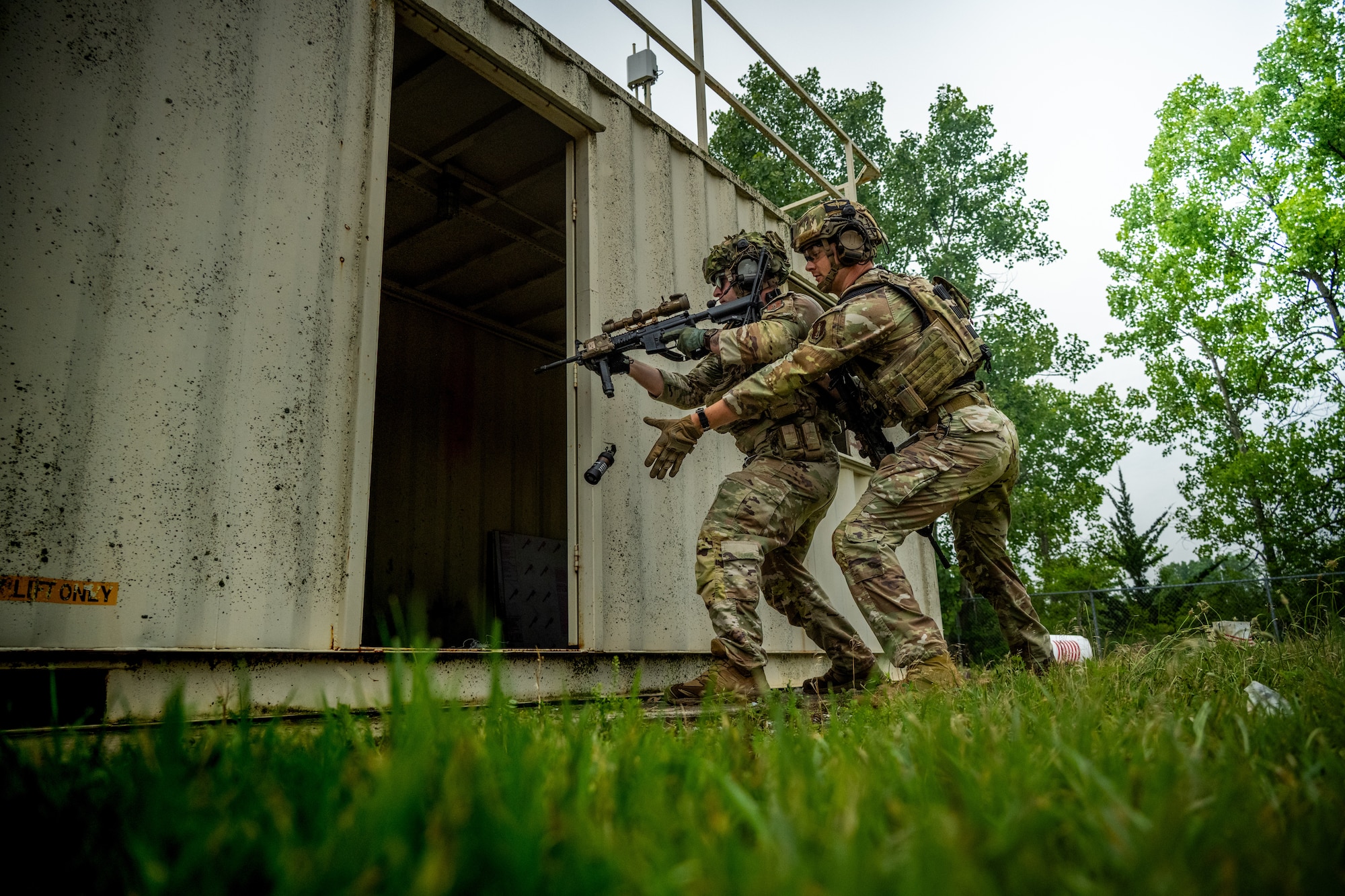 Airmen toss a flash bang grenade into a room