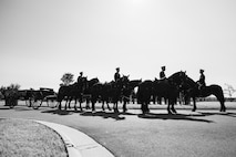 Black and white image of Army Soldiers riding on caisson horses.