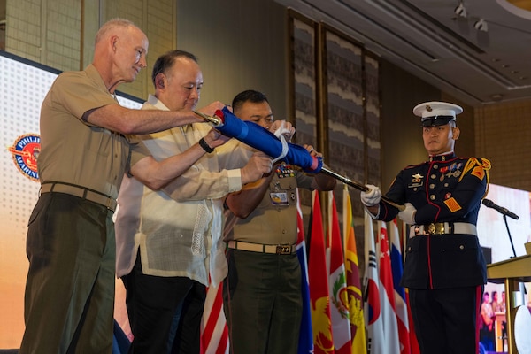 U.S. Marine Corps Lt. Gen. James Glynn, left, commander, U.S. Marine Corps Forces, Pacific, Philippines Secretary of National Defense Gilberto Teodoro Jr., middle, and the 37th Commandant of the Philippine Marine Corps, Maj. Gen. Vicente Blanco, unfurls the Pacific Amphibious Leaders Symposium 2025 flag during the opening ceremony of the 11th iteration of PALS, Manila, Philippines, July 8, 2025. Bringing together experts and leaders from across the Indo-Pacific, PALS fosters collaboration among Allied and partner amphibious and maritime forces to share knowledge and recent operational insights. This year’s symposium hosted senior leaders from 22 participating nations who are committed to a free and open Indo-Pacific, with the objective of strengthening and developing regional relationships. (U.S. Marine Corps photo by Lance Cpl. Roger-Junior Annoh)