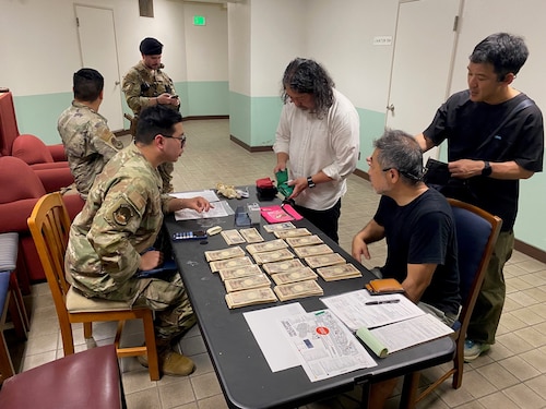A U.S. Air Force member pays Japanese contractors yen.