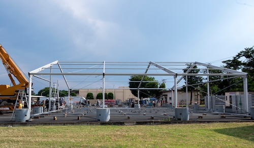 Japanese contractors work to assemble the frame of a tent.