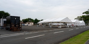White tents are set up in a parking lot for an exercise.