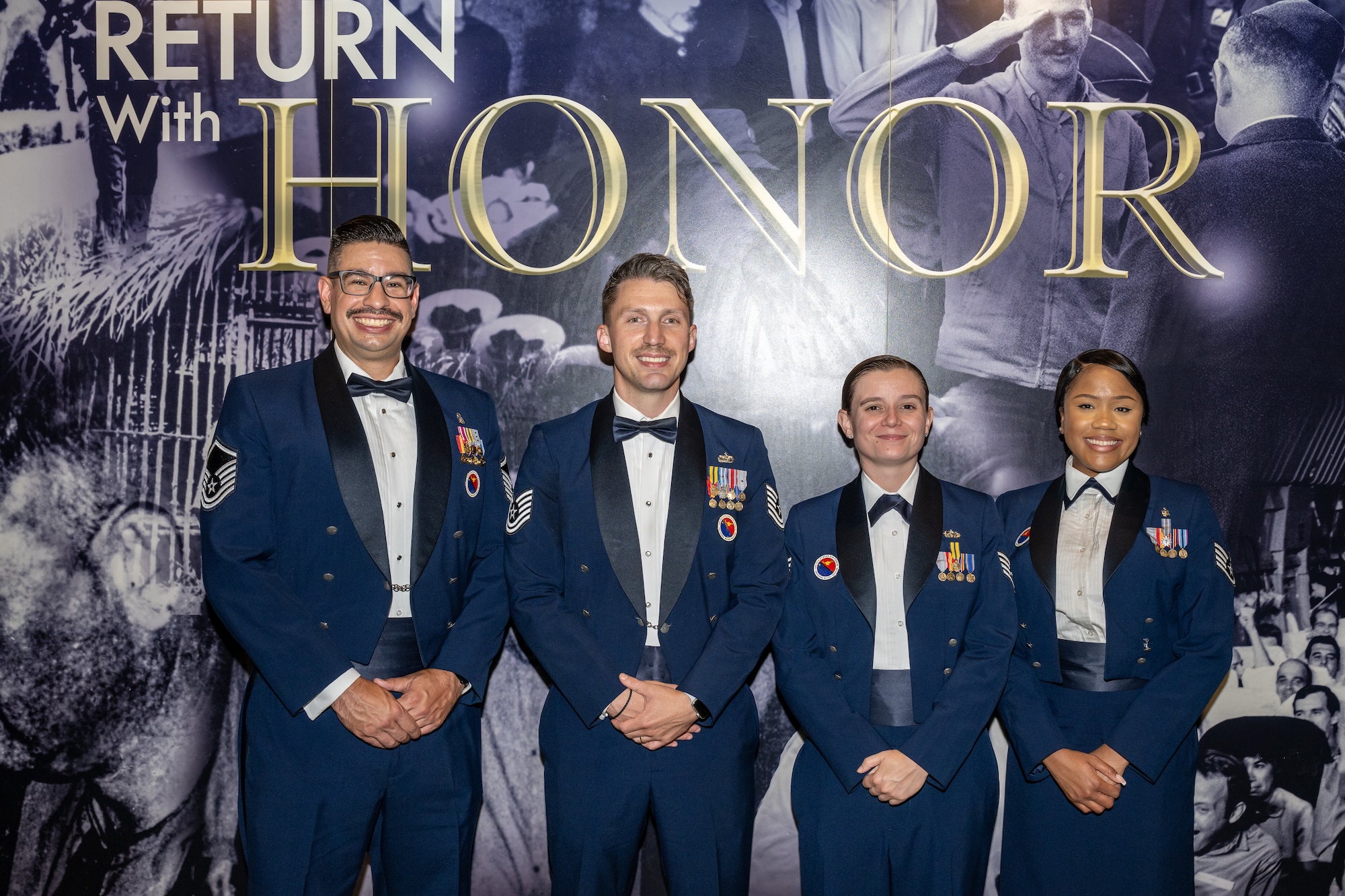 Four Air Force members pose for a group photo in service dress uniforms