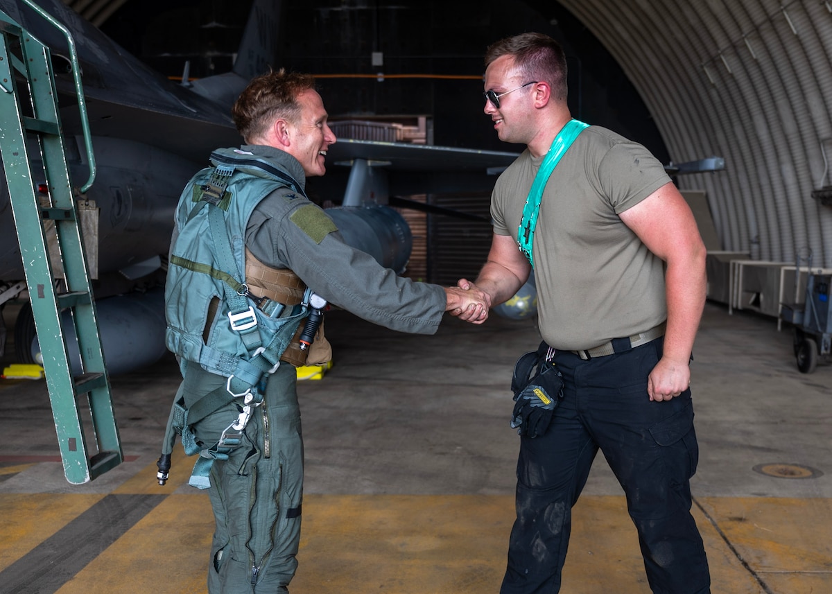 U.S. Air Force Senior Airman Matthew Cover, right, 25th Fighter Generation Squadron F-16 Fighting Falcon crew chief, welcomes Col. Paul Davidson, left, 35th Fighter Wing commander, at Osan Air Base, Republic of Korea, June 26, 2025. The migration of aircraft from Misawa Air Base, Japan to Osan enhanced alignment between U.S. forces in Japan and South Korea, maximizing interoperability for joint operations and bilateral training. (U.S. Air Force photo by Staff Sgt. Sarah Williams)