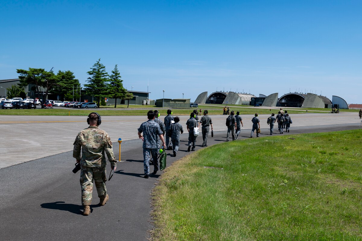 U.S. Air Force Airmen assigned to the 35th Fighter Wing (FW) escort Japan Air Self-Defense Force members to a hangar for training ahead of exercise Resolute Force Pacific (REFORPAC) 2025 at Misawa Air Base, Japan, July 8, 2025. The training provided familiarization with the U.S. Air Force F-16 Fighting Falcon and demonstrated how the USAF conducts refueling operations. Working and training with other nations improves the collective capability to provide support during real-world contingencies across the Indo-Pacific region. (U.S. Air Force photo by Senior Airman Brittany Russell)