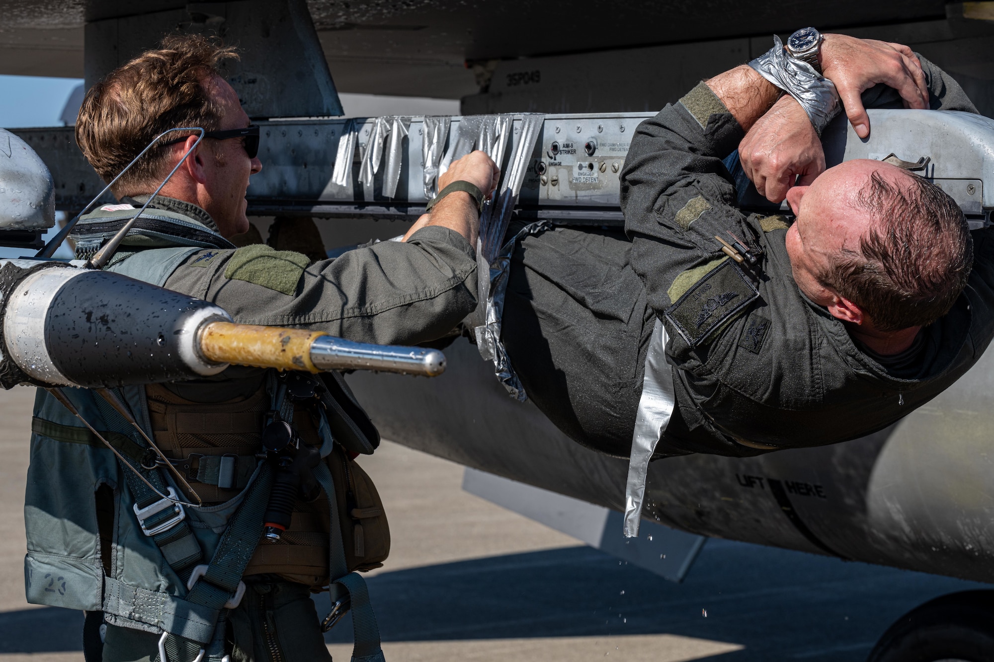 U.S. Air Force Col. Paul Davidson, 35th Fighter Wing (FW) commander, cuts the duct tape holding U.S. Air Force Col. Matthew Kenkel, 35th FW deputy commander, to the wing of a U.S. Air Force F-16 Fighting Falcon during his final, or fini, flight celebration.