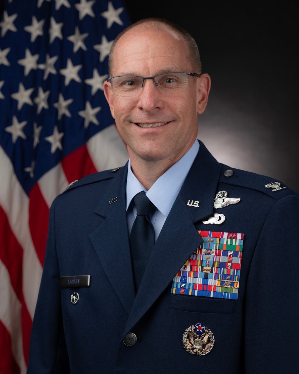 A man in a suit in front of the U.S. flag