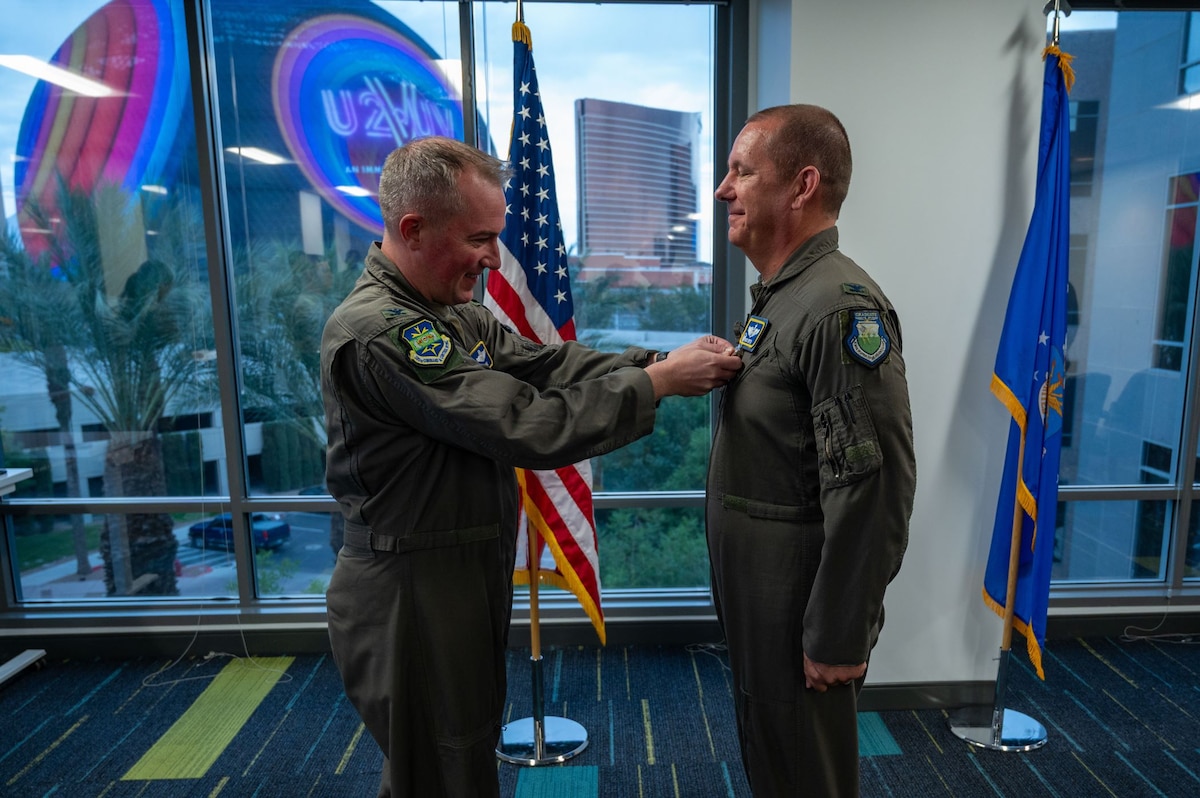 photo of two US Airmen, one is pinning a medal on the others uniform