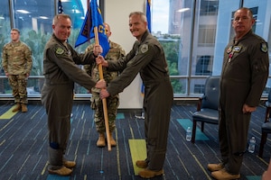 photo of US Airmen holding a unit flag in between them
