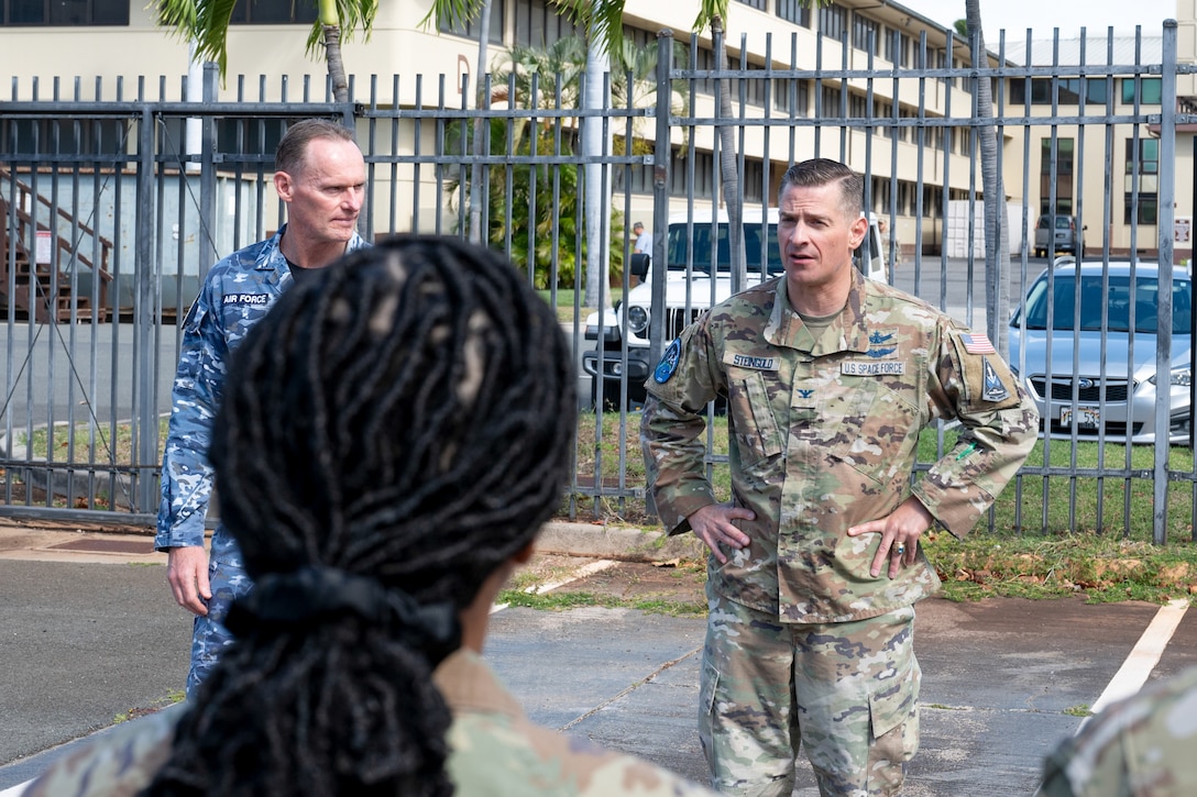 U.S. Space Force Col. Jay Steingold (right) and Royal Australian Air Force Group Captain Darrell May (left) stand outdoors. Col. Steingold has his hands on his hips. They are addressing attendees at the Resolute Space 2025 exercise kickoff near Space Forces Indo-Pacific headquarters in Hawaii.