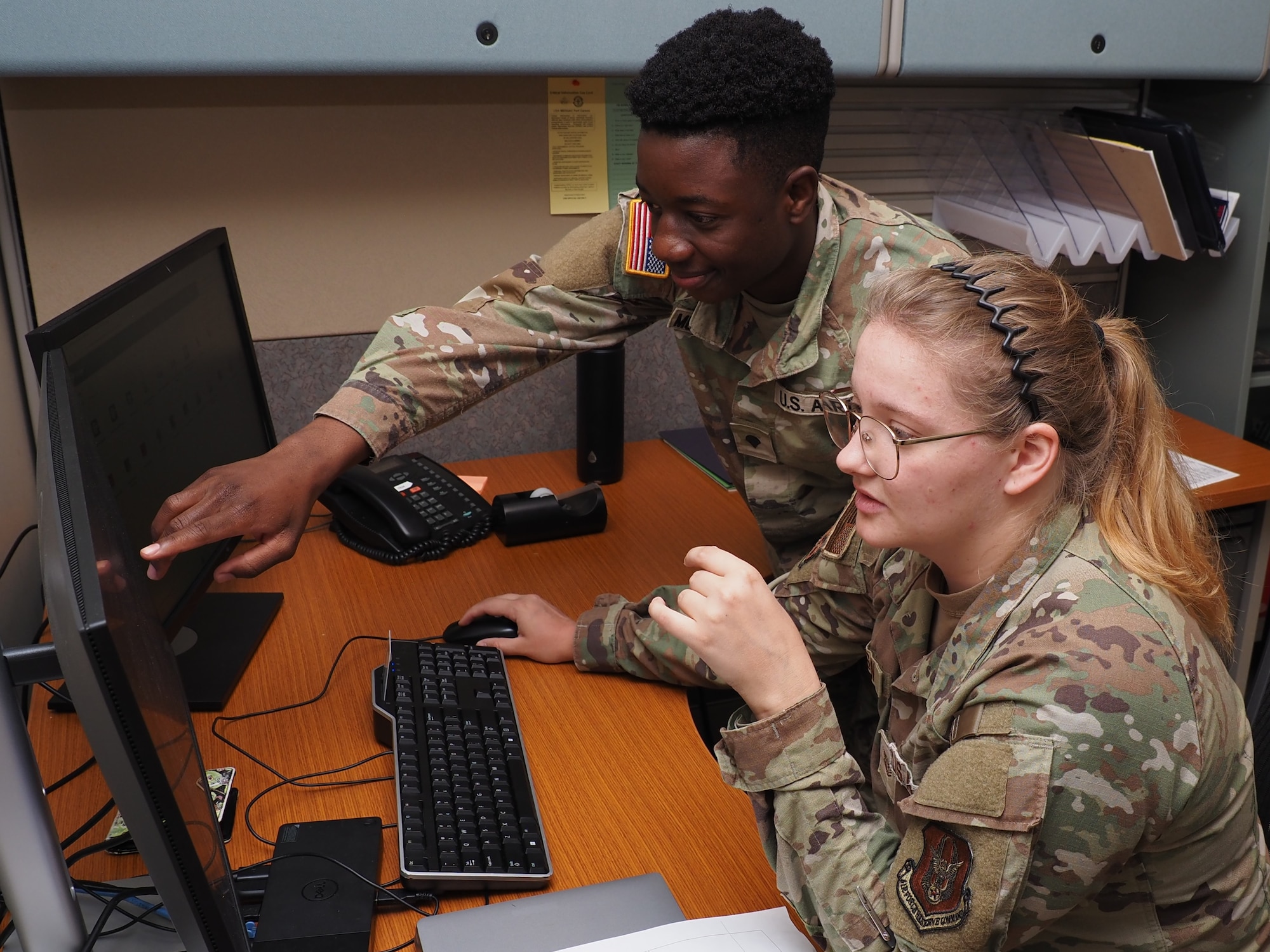 Spc. Muzamhindo Jussy, a behavioral health specialist in the EACH Behavioral Health Department, teaches Tech. Sgt. Ashley Erickson how to enter data from a patient encounter in MHS Genesis.