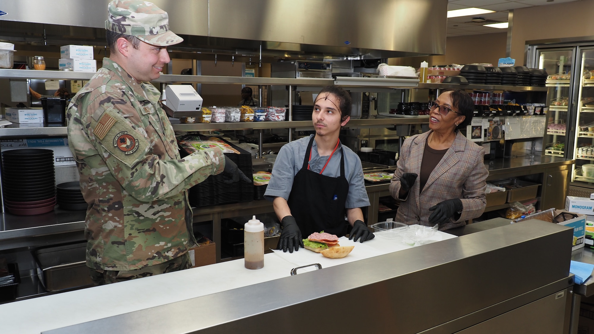 Linda Hunter, right, diet technician, and Savior Troncoso, a cook in the EACH Nutrition Care Division, demonstrate proper assembly of a patient food tray for Master Sgt. Jason Epley, a dietary technician with the 910th Medical Squadron from Youngstown Air Reserve Station, Ohio.