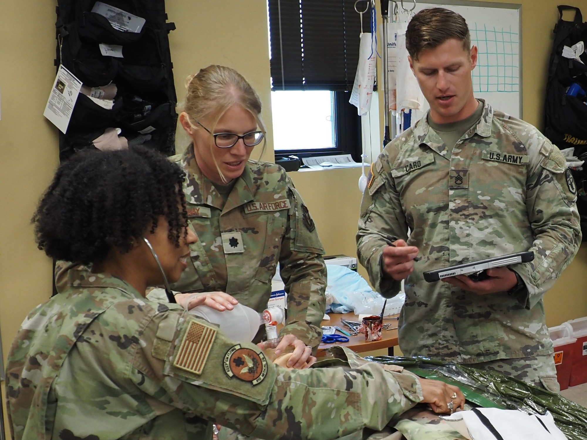 Staff Sgt. Ian Caro, a combat medic assigned to the EACH Department of Education, provides combat casualty care training to Lt. Col. Devin Conway, center, and Senior Master Sgt. Andrea Kirks.