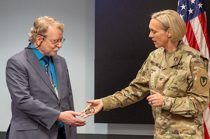 Col. Michelle M. Williams, U.S. Army Financial Management Command commander, presents Terry Hiett, USAFMCOM Military Pay Operations military pay financial management analyst, with a coin from Lt. Gen. Christopher O. Mohan, U.S. Army Materiel Command deputy commanding general and acting commander, at the Maj. Gen. Emmett J. Bean Federal Center in Indianapolis March 13, 2025. Hiett was recognized for his efforts in updating the Army's Enhanced Unit Commander's Financial Reporting tool, which provides commanders with comprehensive views of their Soldiers' pay information, enabling them to ensure accurate and timely pay for their personnel. (U.S. Army photo by Mark R. W. Orders-Woempner)