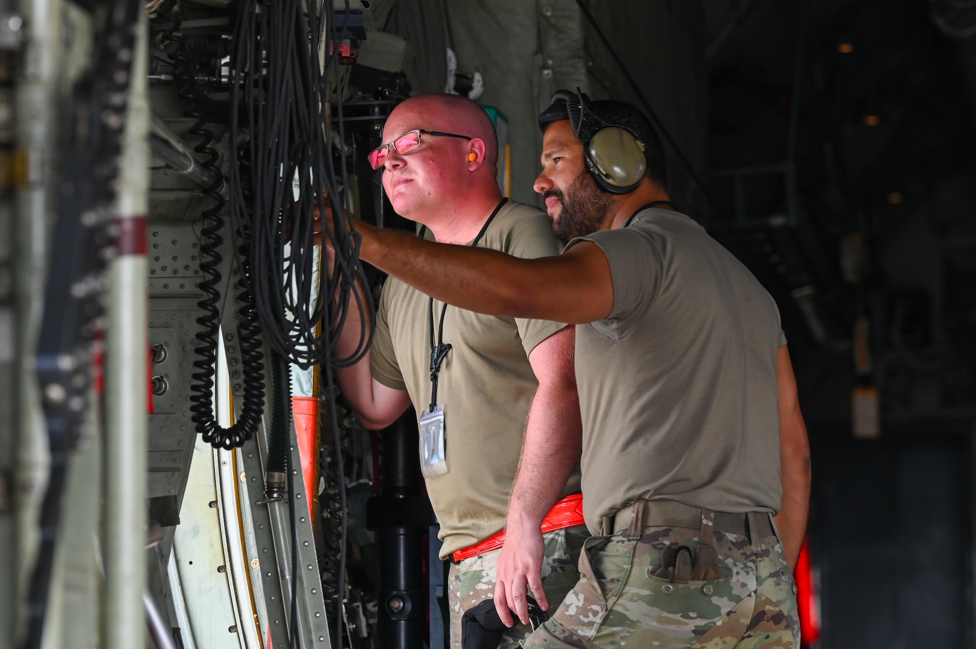 U.S. Air Force Airmen assigned to the 317th Airlift Wing observe activity from the side hatch of a C-130J Super Hercules during a Combat Readiness Inspection at Dyess Air Force Base, Texas, July 1, 2025. The Air Mobility Command inspection tested the wing’s ability to rapidly deploy mission-ready Airmen and equipment under realistic, time-constrained scenarios. (U.S. Air Force photo by Airman 1st Class Adrien Tran)