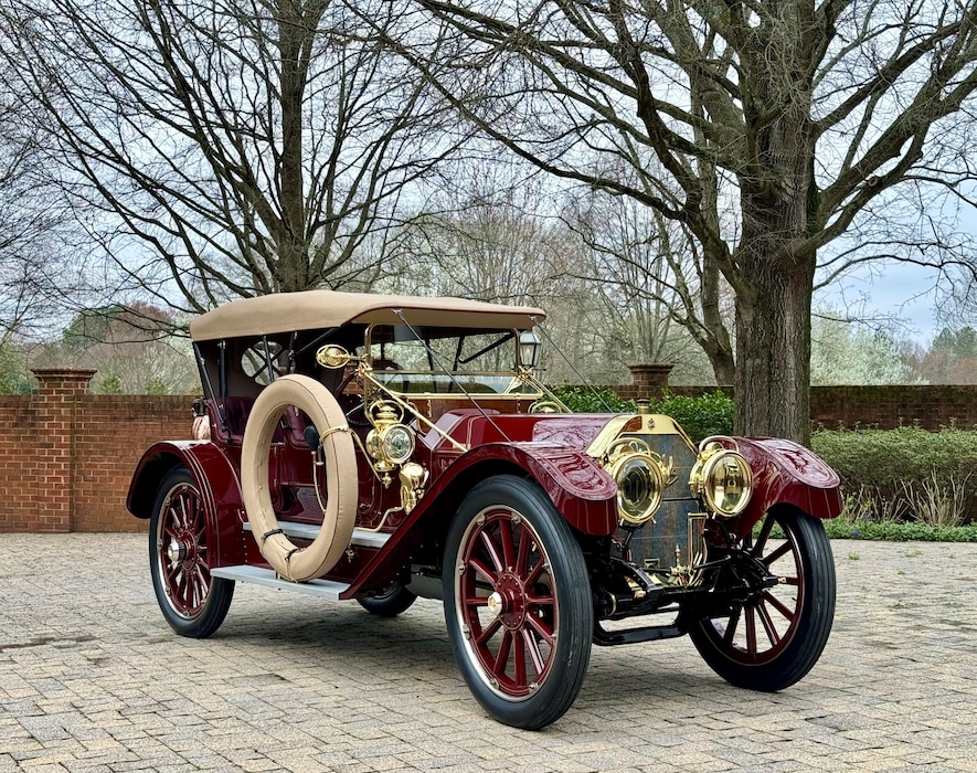 Red antique car parked on brick paver driveway
