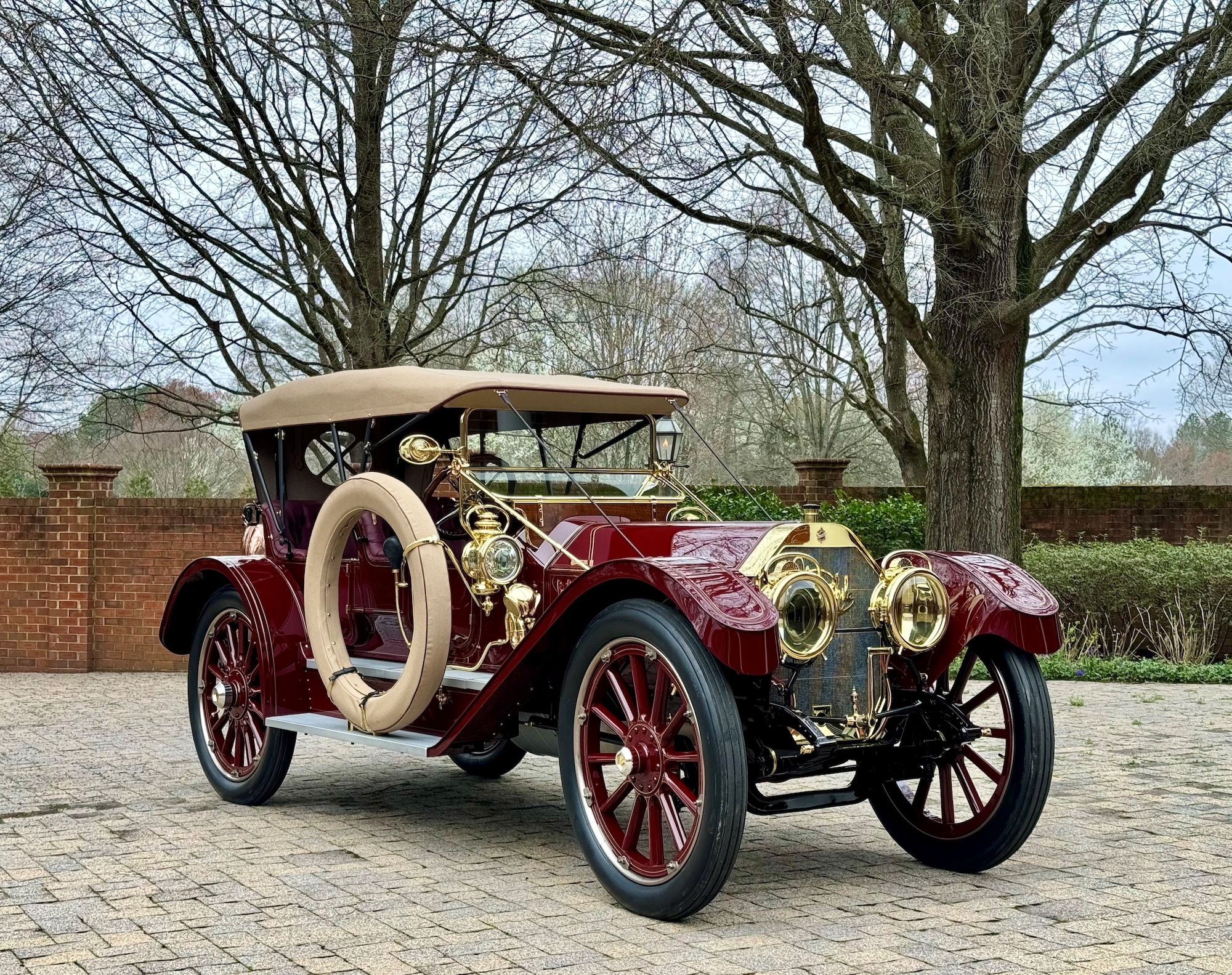 Red antique car parked on brick paver driveway