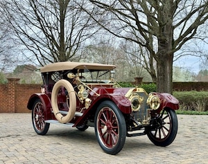 Red antique car parked on brick paver driveway