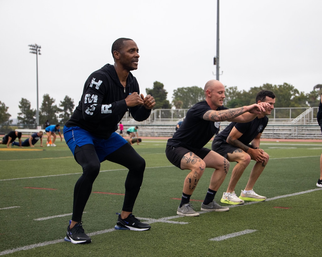 U.S. Marine Corps Sgt. Maj. Theodore Ingram, left, the sergeant major of I Marine Expeditionary Force Information Group, conducts air squats with Marines during unit physical training at Marine Corps Base Camp Pendleton, California, June 27, 2025. Unit PT increases unit cohesion, morale and physical readiness across the group. (U.S. Marine Corps photo by Lance Cpl. Fabian Ortiz)