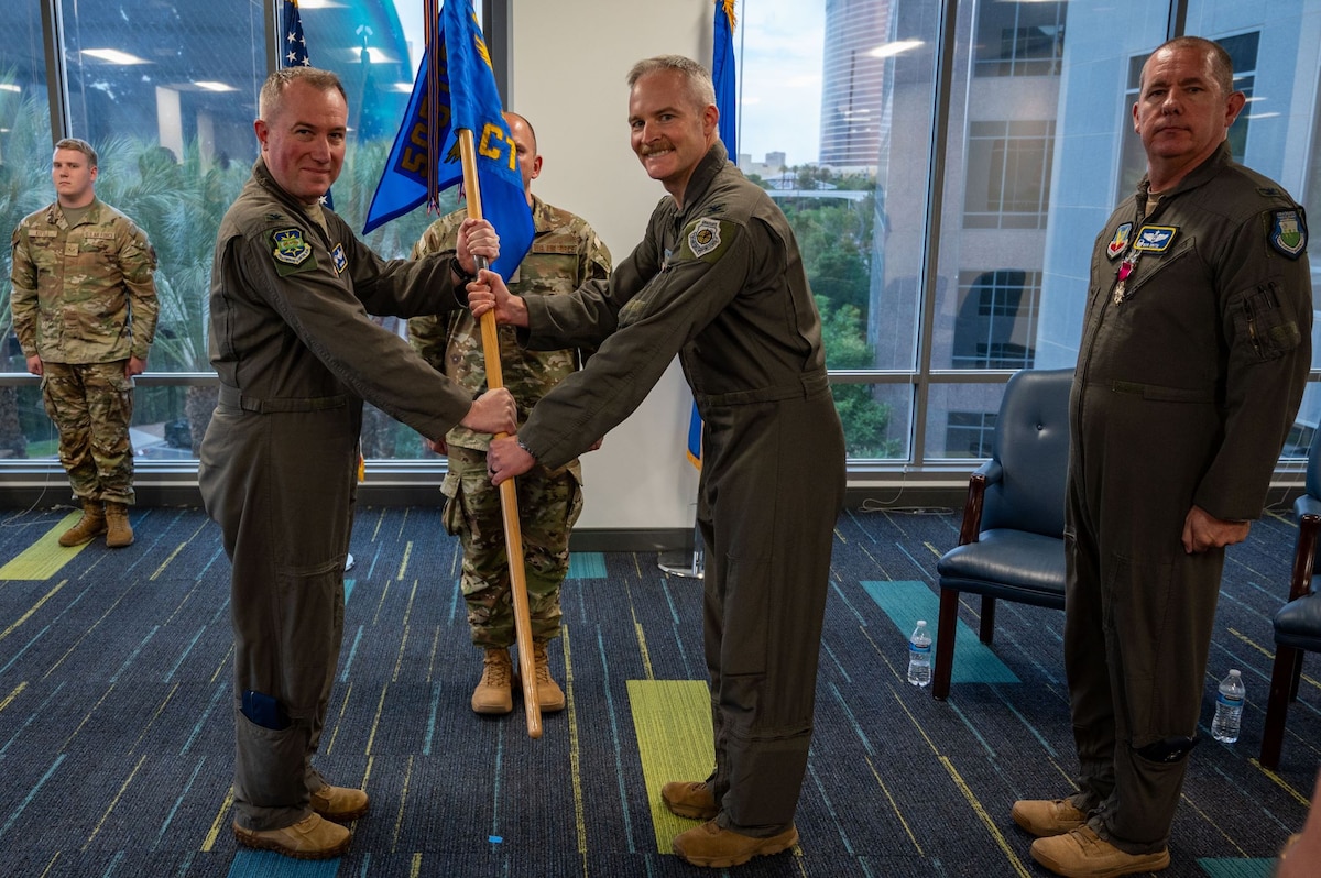 photo of US Airmen holding a unit flag in between them