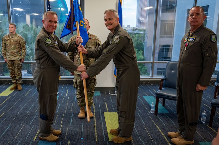 photo of US Airmen holding a unit flag in between them