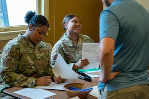 Two airmen dressed in camouflage record information about an individual in the inactive Ready Reserve