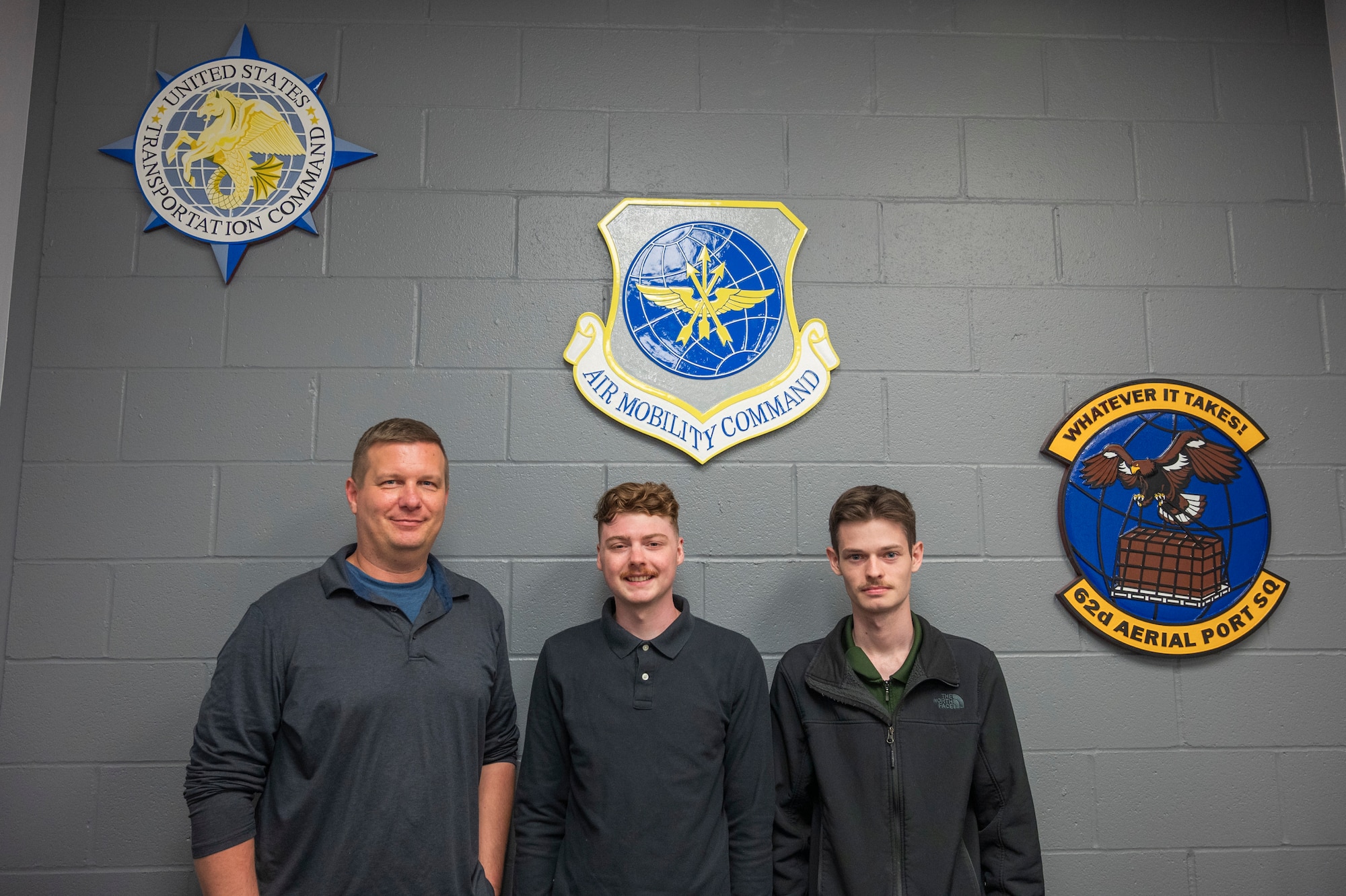 U.S. Air Force Master Sgt. Frank Brooks, 62d Aerial Port Squadron gateway manager, left, Senior Airman Hunter Williams, center, and Staff Sgt. Christopher, both 62d APS contractor officer representatives, stand in their office at the Seattle-Tacoma International Airport, Washington, July 3, 2025.
