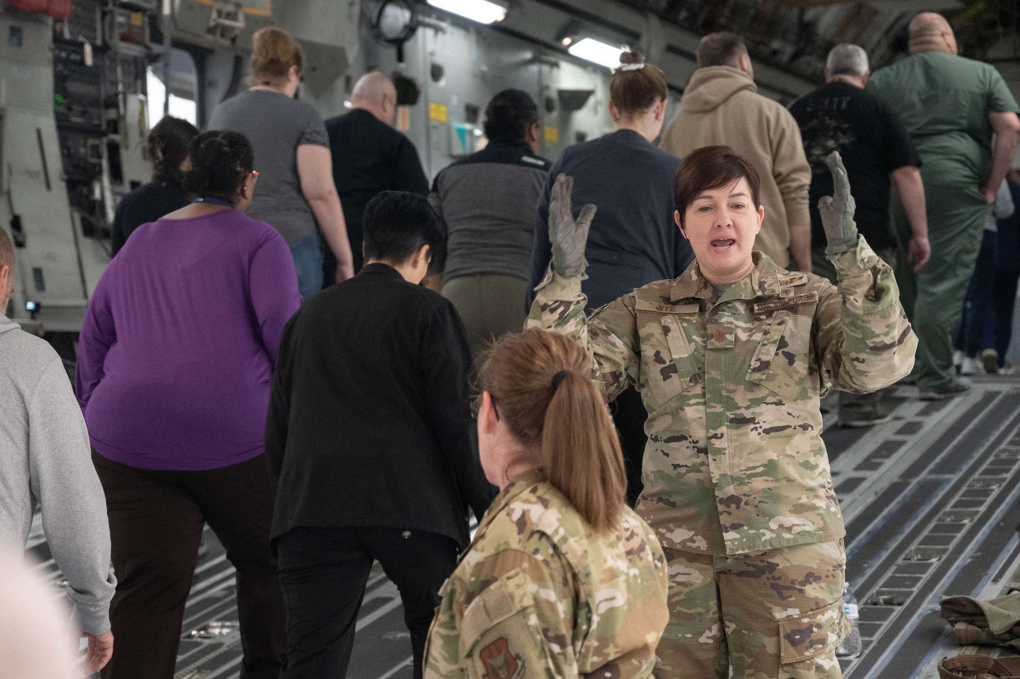 a woman in camouflage directs civilians on to an aircraft