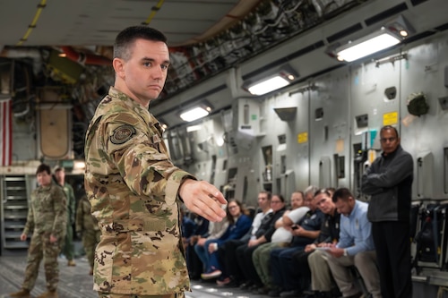 a man in air force camouflage directs people onto an aircraft