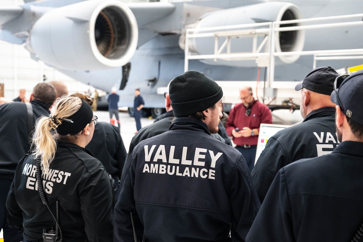 a group of emergency responders stands in front of a C-17 Globemaster Aircraft