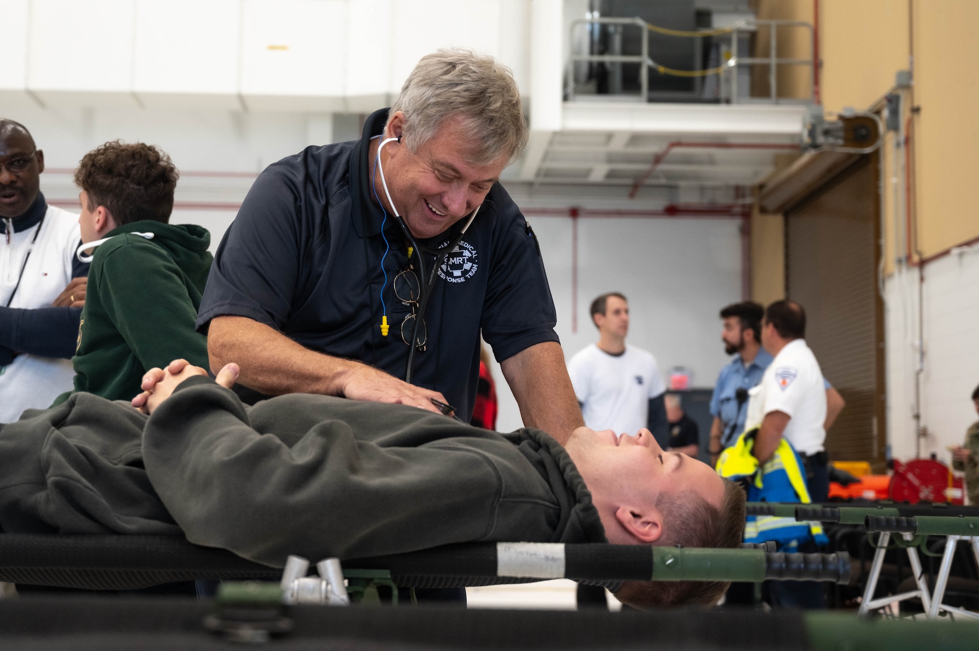 a doctor listens to the heartbeat of a young man on a stretcher