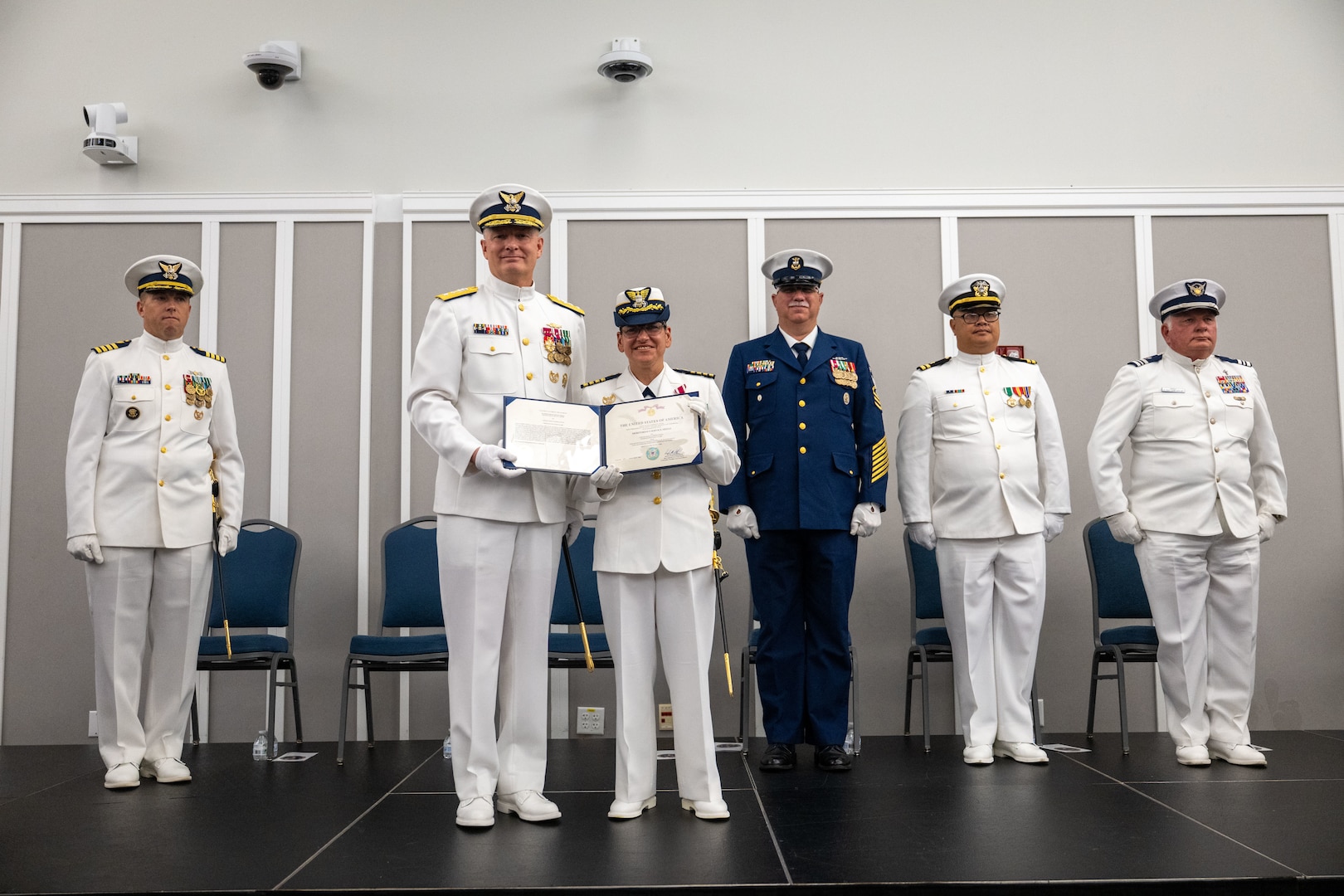 Capt. Janet D. Espino-Young receives an award before transferring command of Coast Guard Sector Jacksonville to Capt. Jason C. Aleksak during a change of command ceremony at the Jacksonville Public Library in Jacksonville, Florida, July 9, 2025. Rear Adm. Douglas Schofield, commander, Coast Guard Southeast District, presided over the ceremony. (U.S. Coast Guard photo by Petty Officer 3rd Class Kace White)