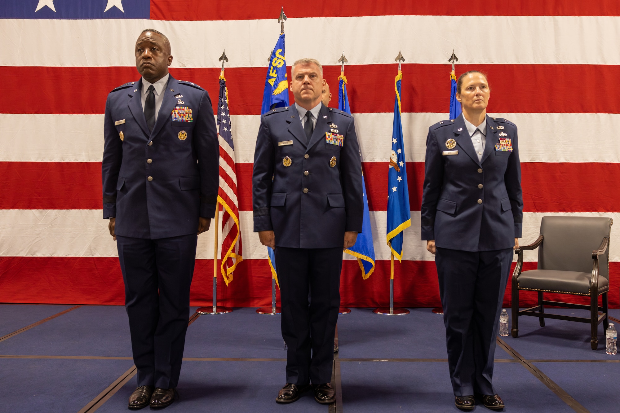Several people stand on stage at attention