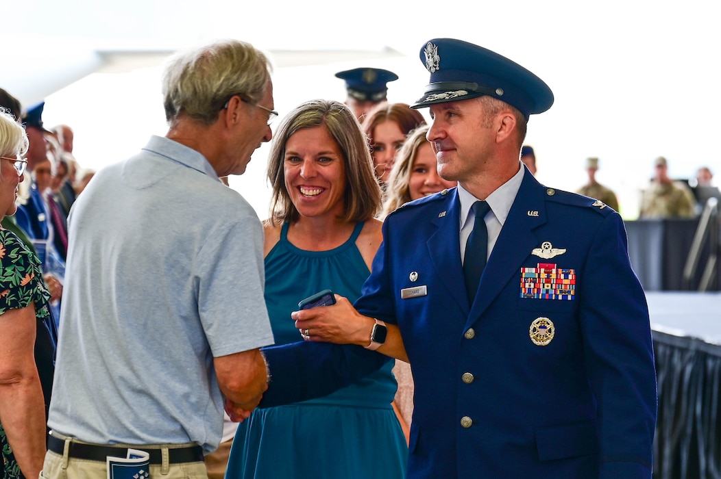 A commander in service dress greets an attendee at a change of command ceremony.