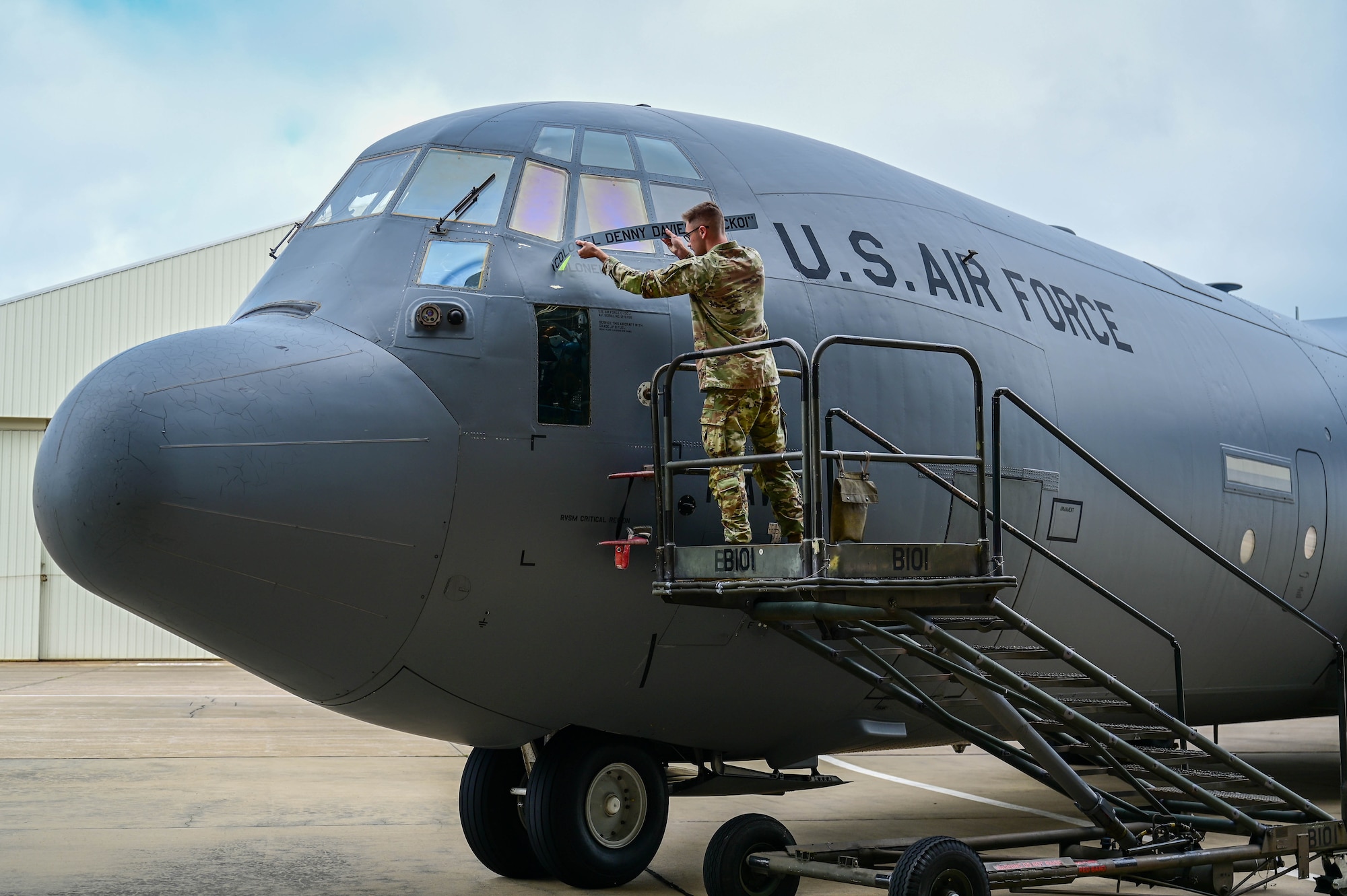 An Airman in uniform reveals the name of the new commander on an aircraft.
