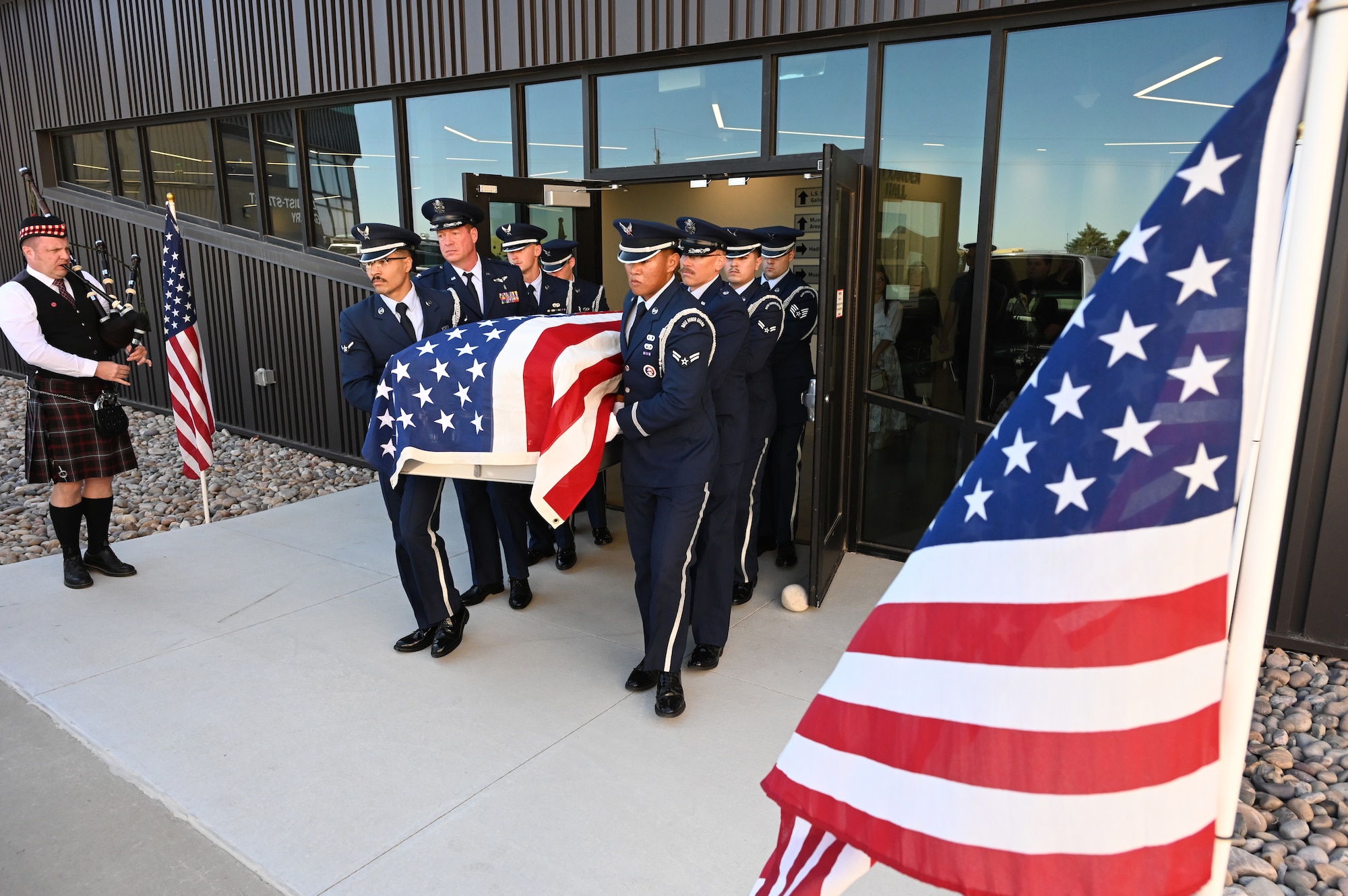 Honor guard members exit the museum carrying a casket holding the remains of Lt. Wilson.