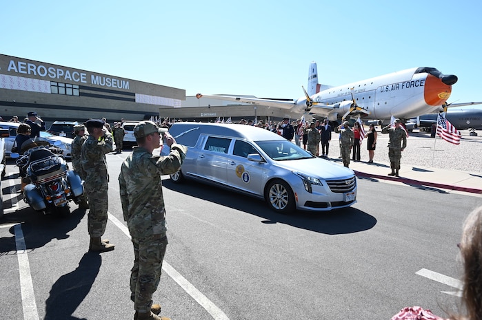 Airmen lining a road salute a hearse carrying the remains of Lt. Wilson.