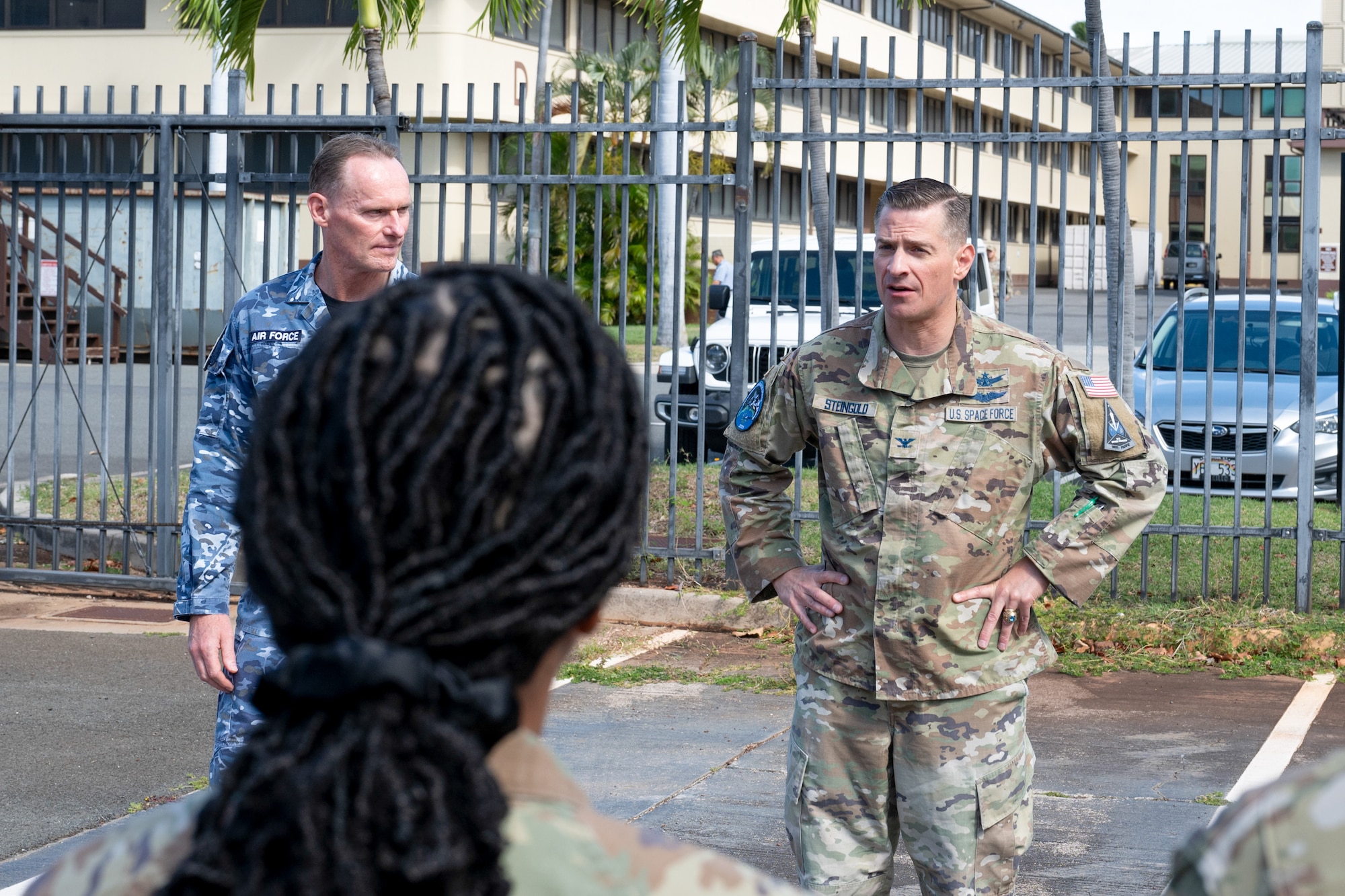 U.S. Space Force Col. Jay Steingold (right) and Royal Australian Air Force Group Captain Darrell May (left) stand outdoors. Col. Steingold has his hands on his hips. They are addressing attendees at the Resolute Space 2025 exercise kickoff near Space Forces Indo-Pacific headquarters in Hawaii.