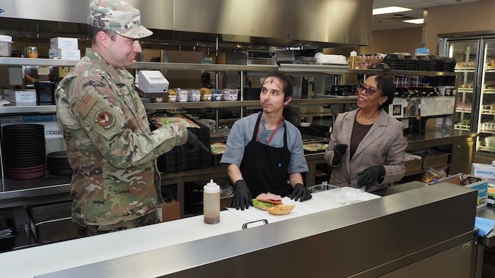 Linda Hunter, right, diet technician, and Savior Troncoso, a cook in the EACH Nutrition Care Division, demonstrate proper assembly of a patient food tray for Master Sgt. Jason Epley, a dietary technician with the 910th Medical Squadron from Youngstown Air Reserve Station, Ohio.