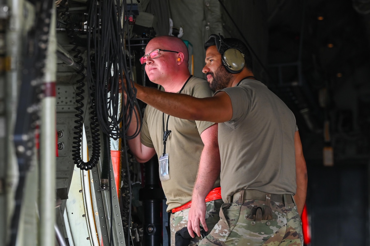 U.S. Air Force Airmen assigned to the 317th Airlift Wing observe activity from the side hatch of a C-130J Super Hercules during a Combat Readiness Inspection at Dyess Air Force Base, Texas, July 1, 2025. The Air Mobility Command inspection tested the wing’s ability to rapidly deploy mission-ready Airmen and equipment under realistic, time-constrained scenarios. (U.S. Air Force photo by Airman 1st Class Adrien Tran)