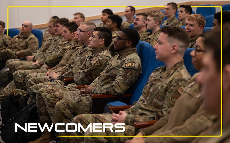 Airmen seated while receiving a briefing. There's a yellow border going around the image with the text "Newcomers"